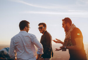 A group of men smiling together at sunset