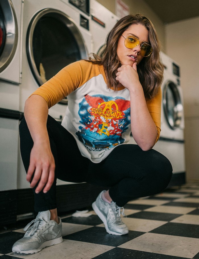 A woman wearing an aerosmith t-shirt and sneakers