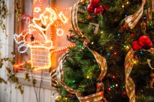 A close-up shot of a the mid-section of a Christ,mas tree. In the background, there are red, white and blue white lights on the wall.