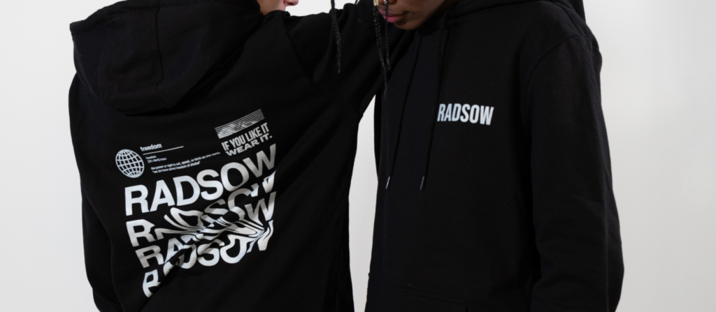 Two people model a hoodie, with a small logo on the front, and a large one on the back