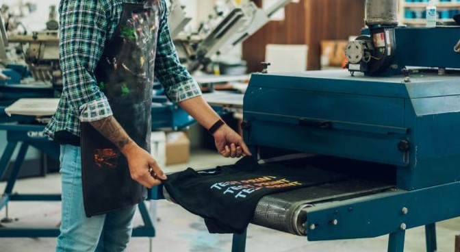 A man prints logos onto a t-shirt