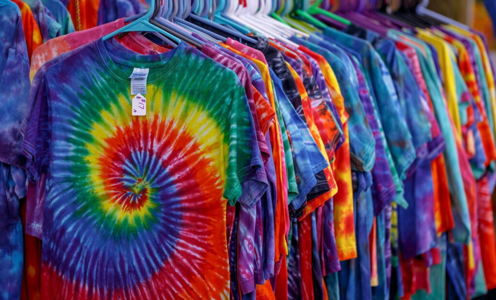 A clothes rail of tie-dye t-shirts. With the rainbow spiral design at the front