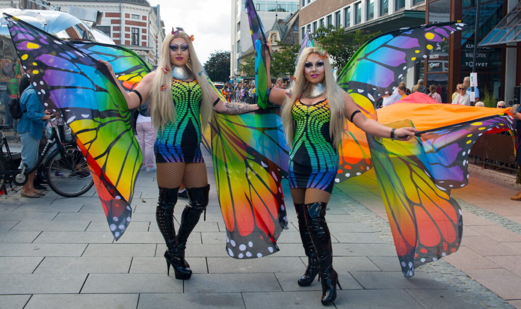 Two women wearing extravagant outfits with rainbow wings