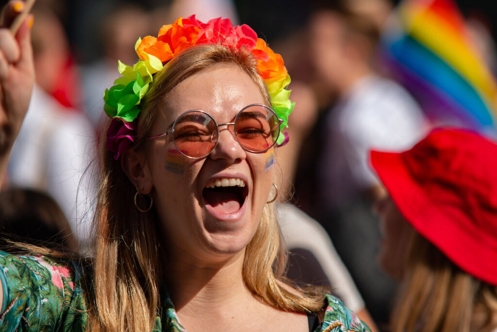 A woman smiling in a summer outfit and rainbow headband