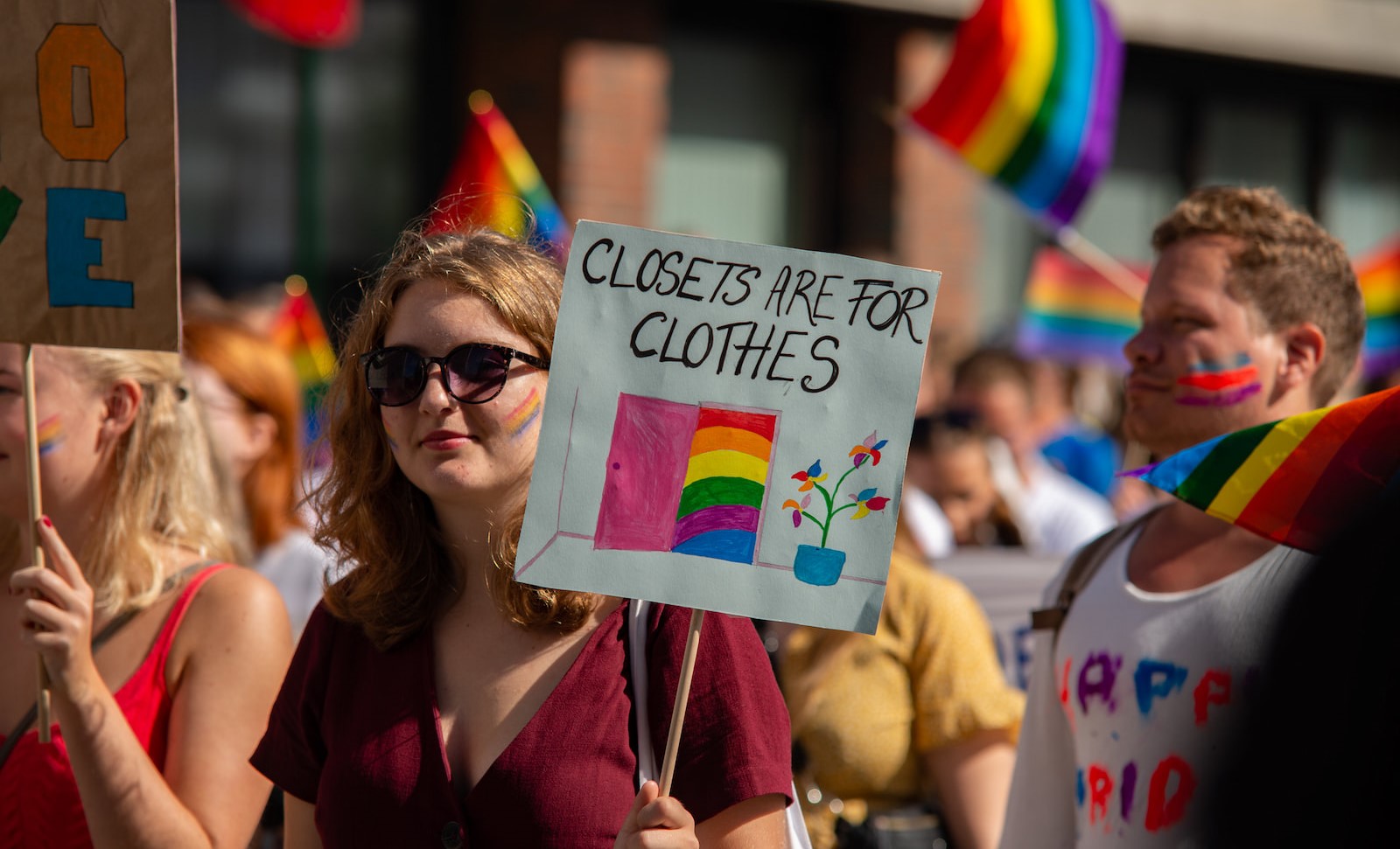A girl at a Pride event with a sign that says: Closets are for Clothes