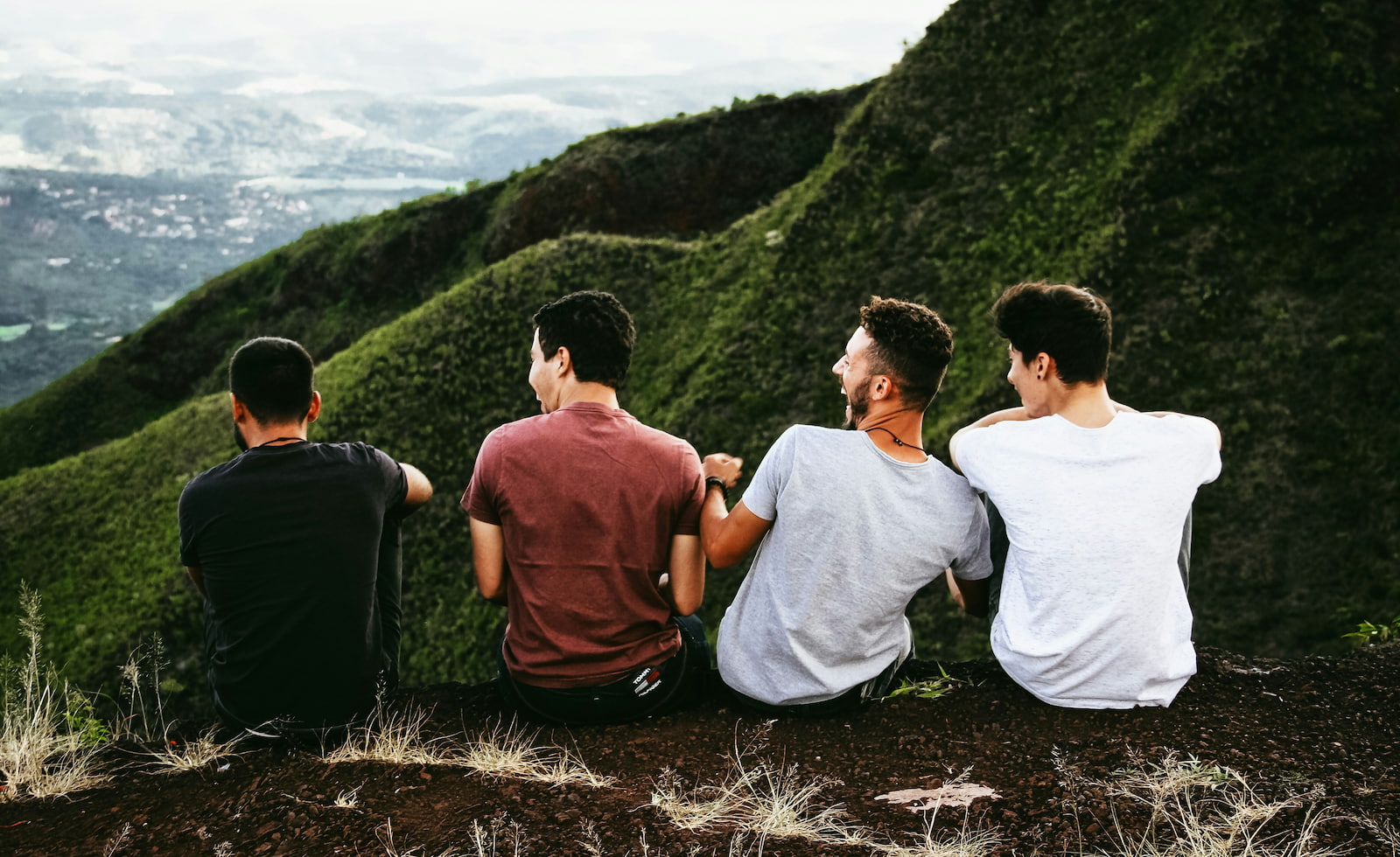 Four young men on a mountain top enjoying the views, and wearing blank t-shirts