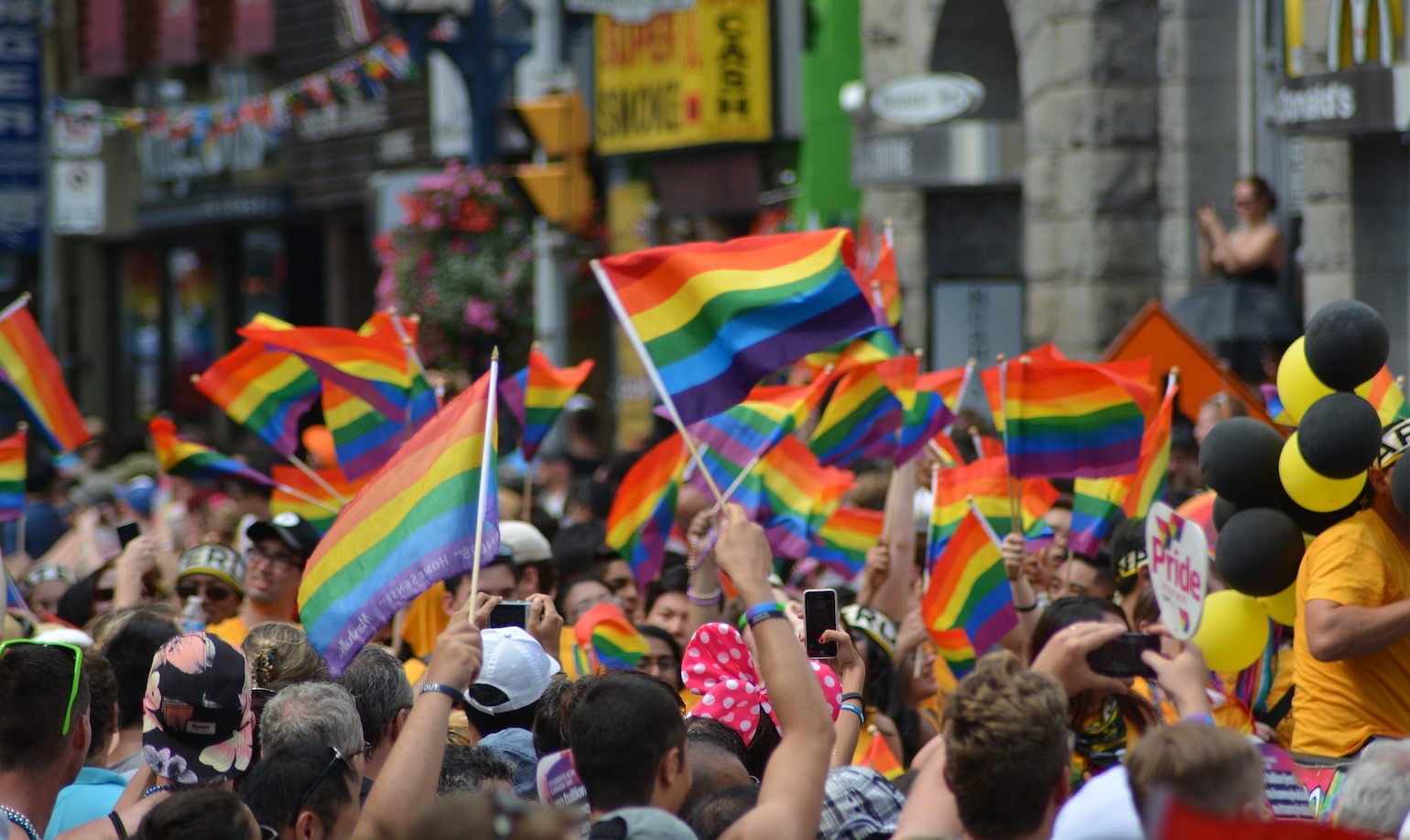 Crowds of people waving rainbow flags for Pride Month