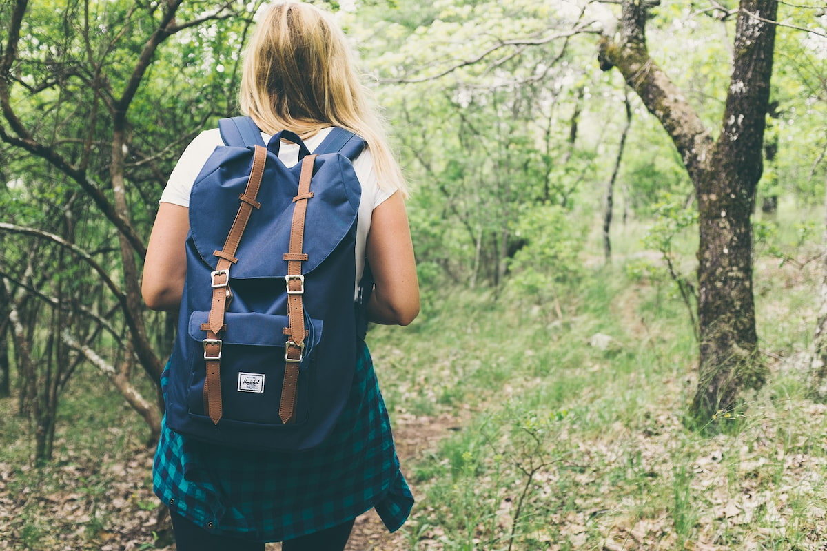 A woman walks in the woods with a backpack