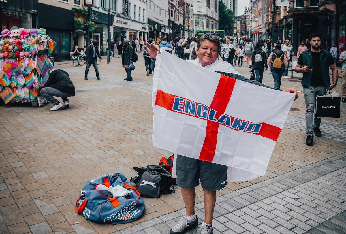 A street vendor holds up an England football flag