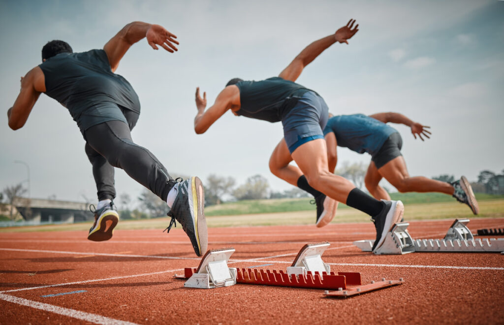 3 men starting a sprinting race on an athletics track