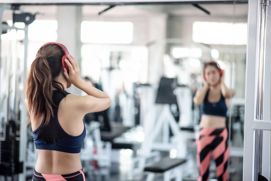 A woman in the gym wearing sportswear looks at herself in the mirror