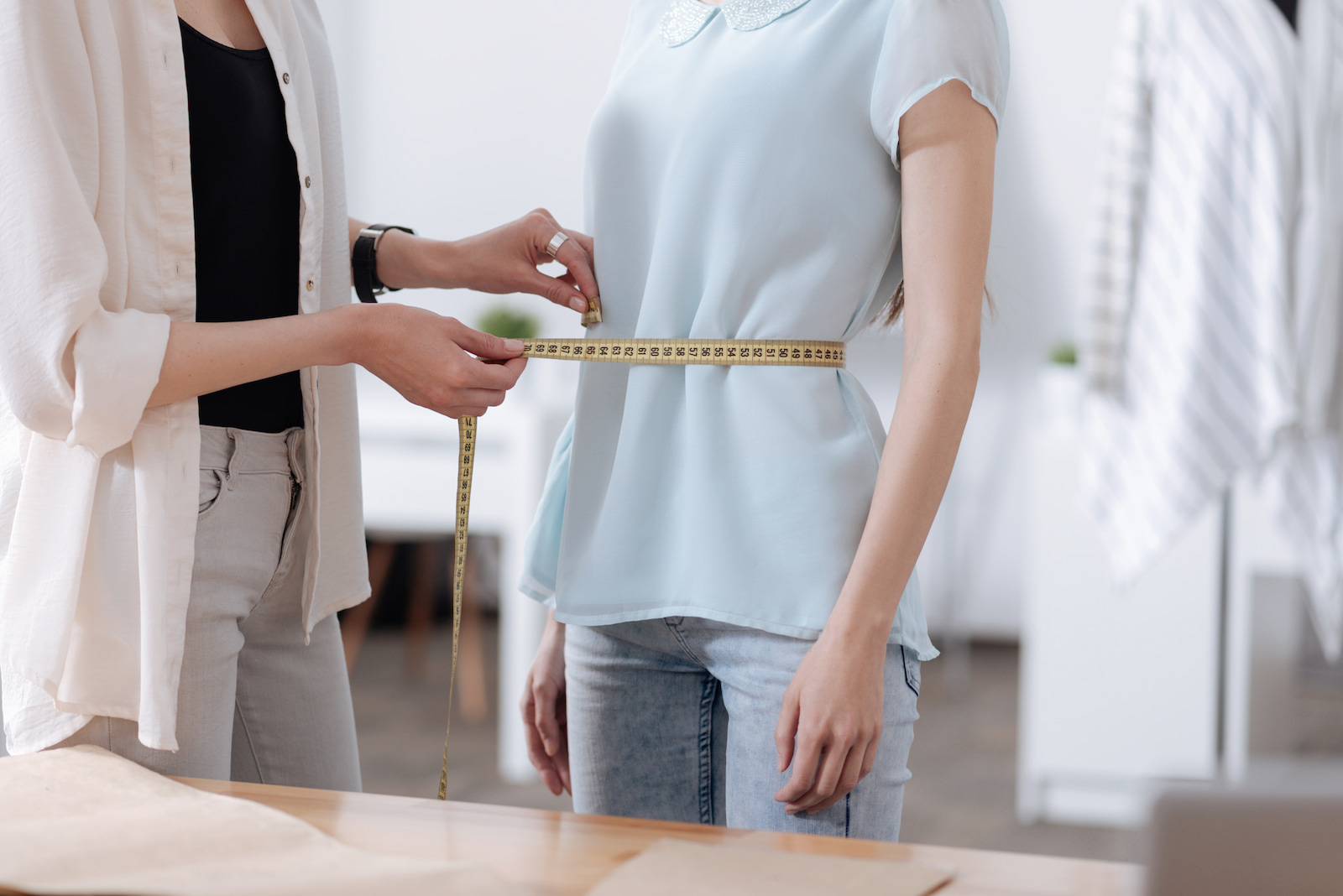 A woman measuring another's waist