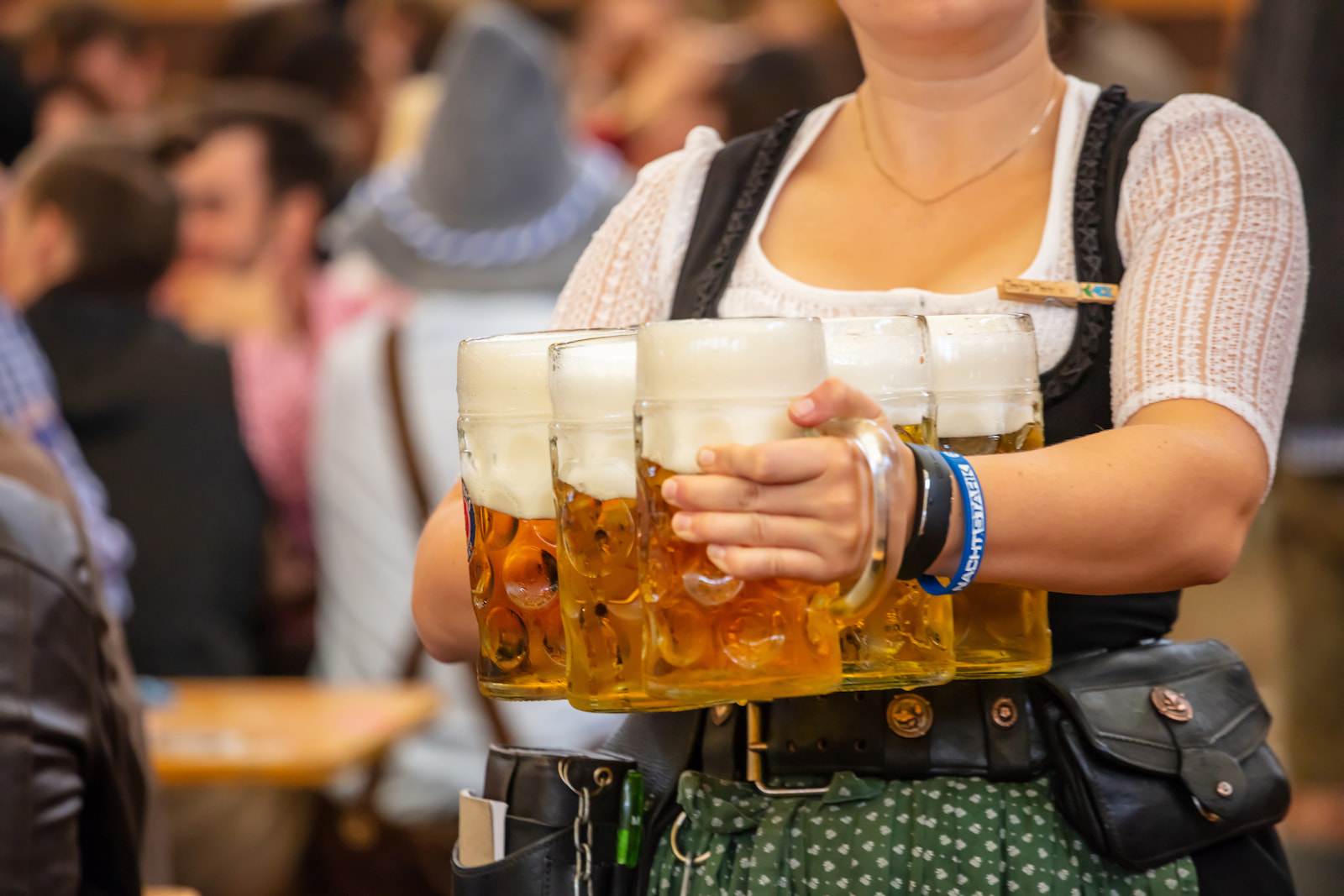 A barmaid carries many large beers in a beer hall at Oktoberfest