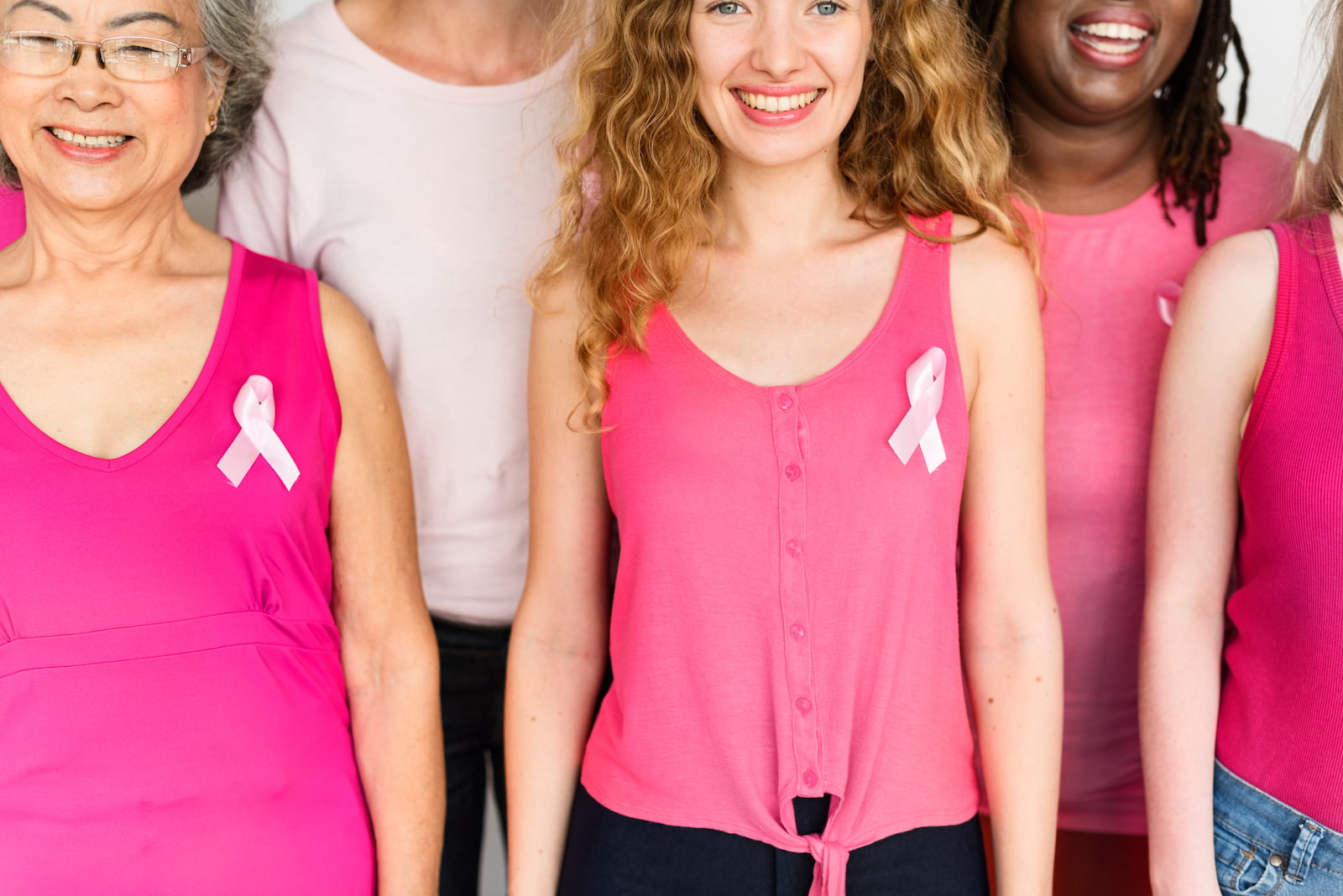 A group of women wearing pink ribbons and pink tops in support of breast cancer